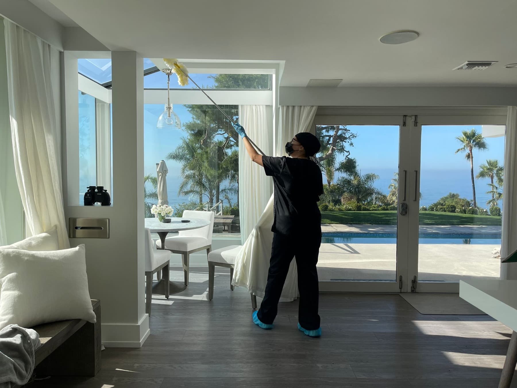 Leaf team member cleaning tall windows in a luxury oceanview home